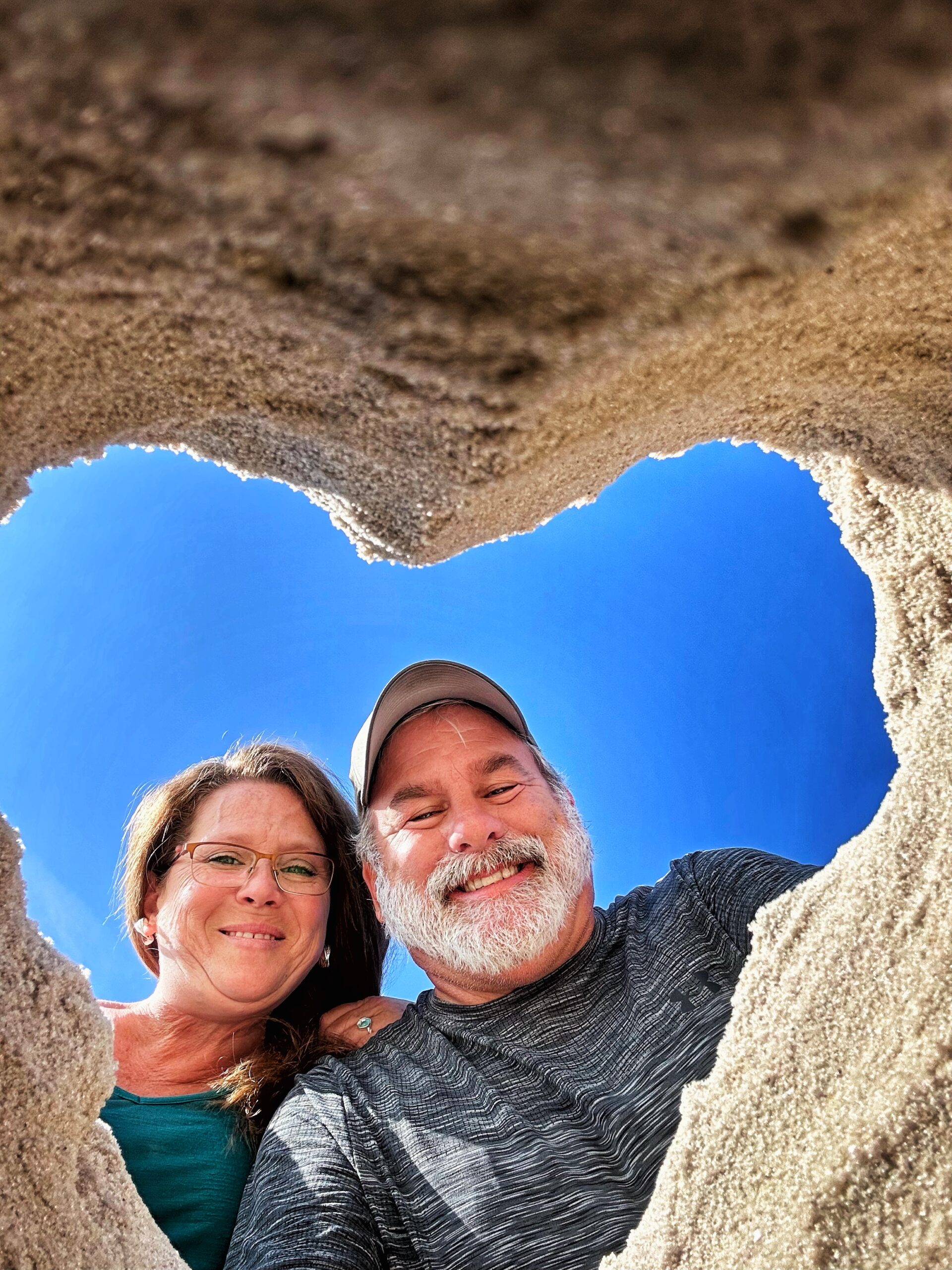 Jimmy and Lisa doing a heart selfie in the sand enjoing thr rv life