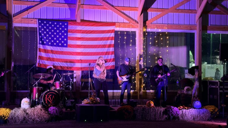 Kate Watson and the band on stage under the American flag at the Barn Party