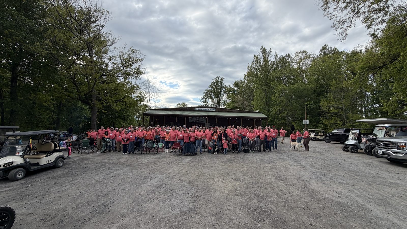 FindUsCamping Village group photo at a campout with golf carts and RVers in matching shirts
