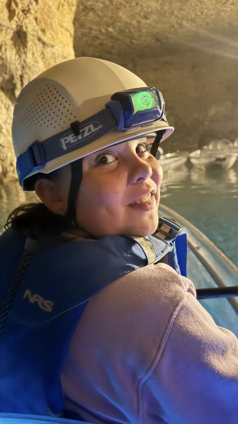Young villager smiling in a cave kayak helmet