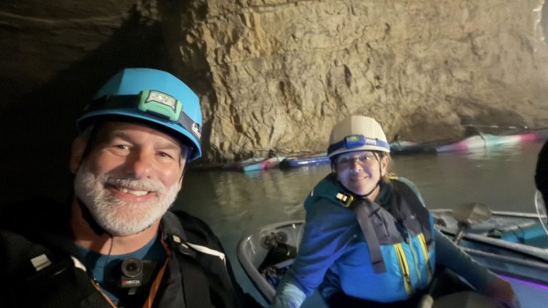 Villagers in helmets kayaking inside a cave