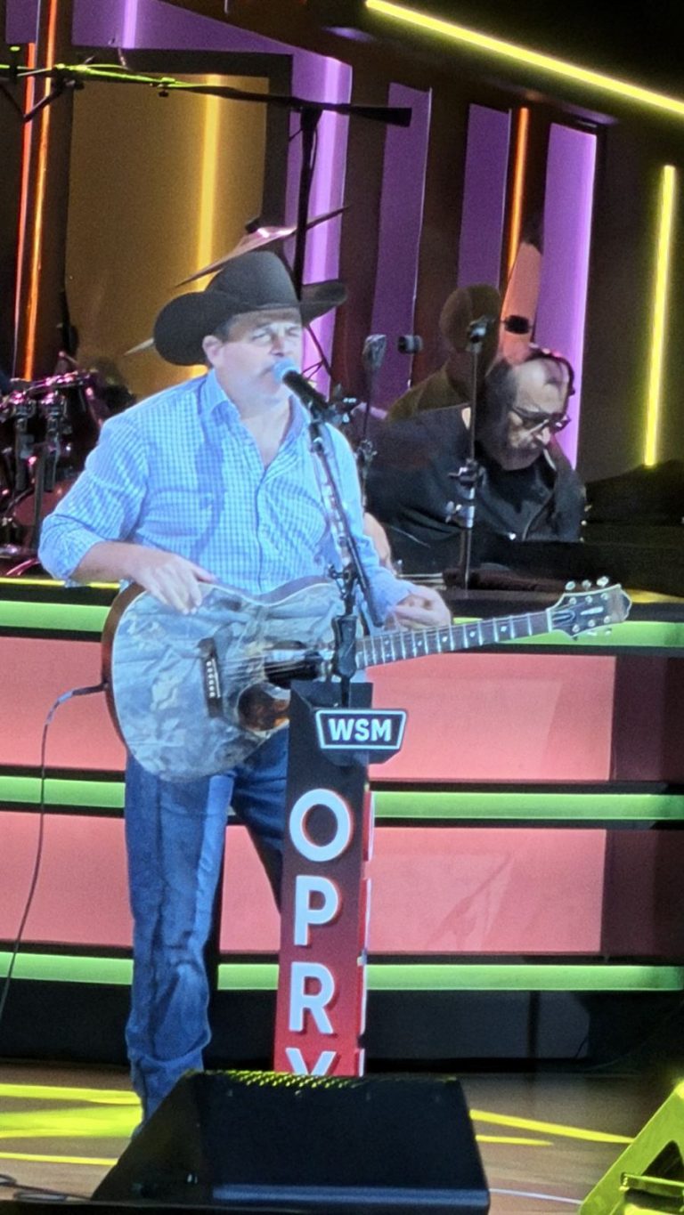 Country singer with a guitar at the Opry microphone