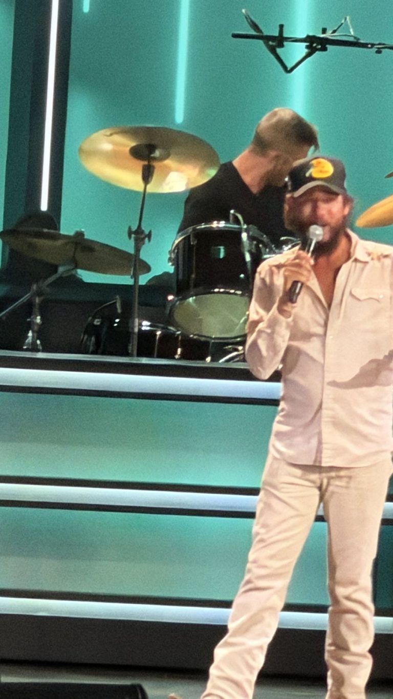 Singer in a ball cap performing at the Grand Ole Opry