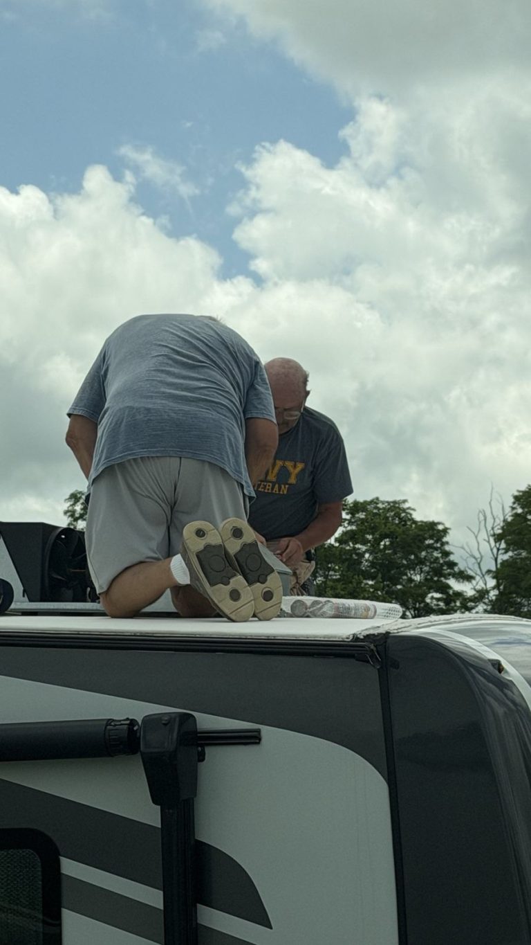 Two villagers working together on an RV roof repair