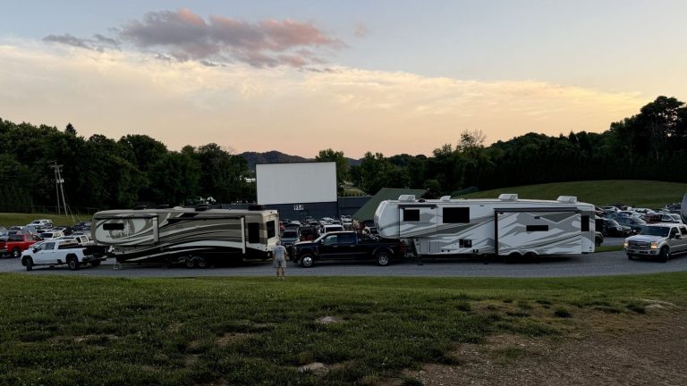 FindUsCamping RVs parked at a drive-in theater at sunset